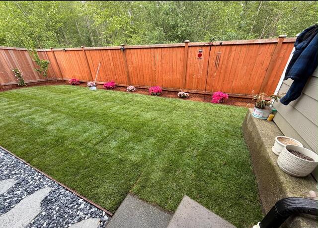 Wide freshly installed lawn with cedar fence and flower beds