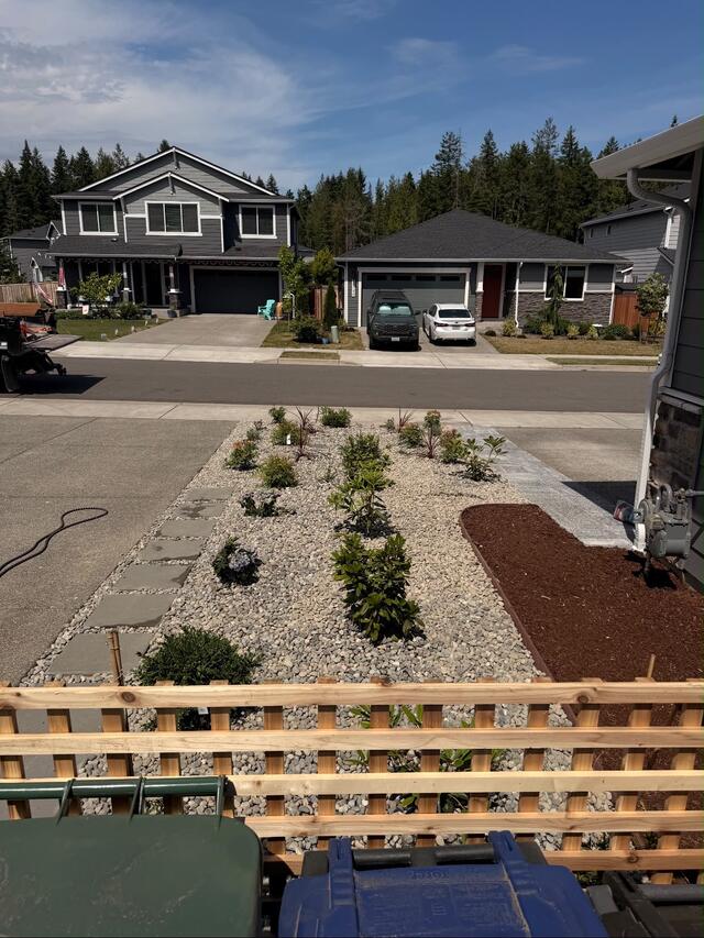 Front yard with new shrub beds, rock mulch, and a low retaining wall