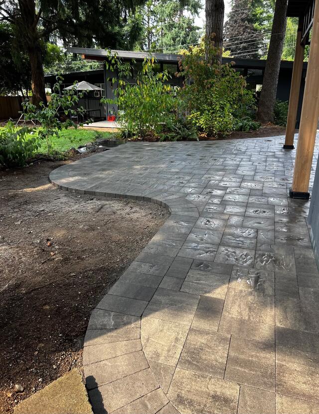 Curved paver patio meeting a healthy green lawn