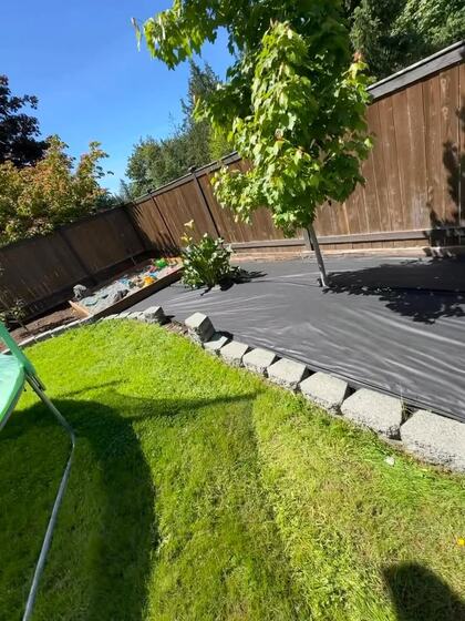 Landscape fabric rolled out along a lawn edge with a stone border and new plantings
